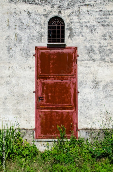 Fototapeta Una porta di metallo dipinta di rosso su un muro bianco