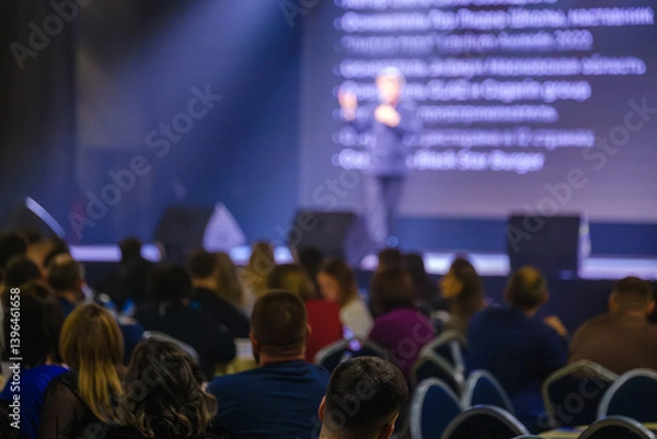 Obraz Focused audience members attentively listen to a keynote speech during a professional conference.
