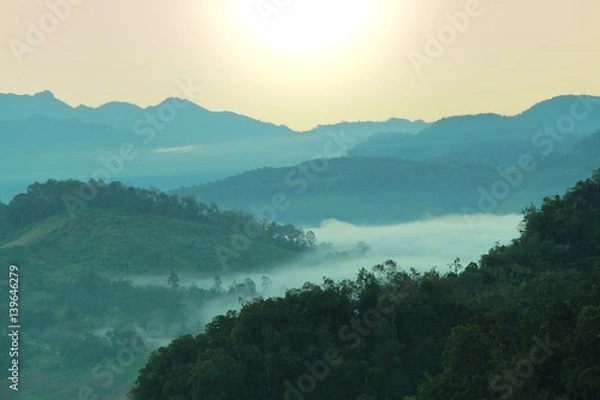Fototapeta Morning mountain landscape with waves of fog at baan ja bo, Mae Hong Son, Northern Thailand. Waves of clouds in the mountain peaks covered with coniferous deciduous forests