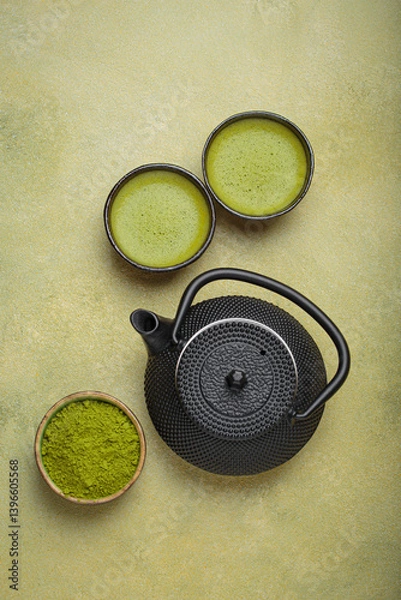 Obraz Matcha tea in cups, black iron teapot and matcha powder on a green background, a relaxing and inviting atmosphere for a traditional japanese tea ceremony