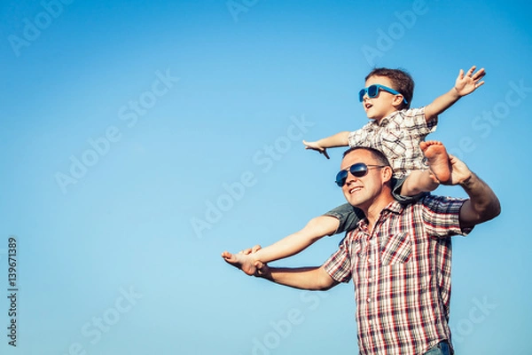 Obraz Dad and son in sunglasses playing in the park at the day time.