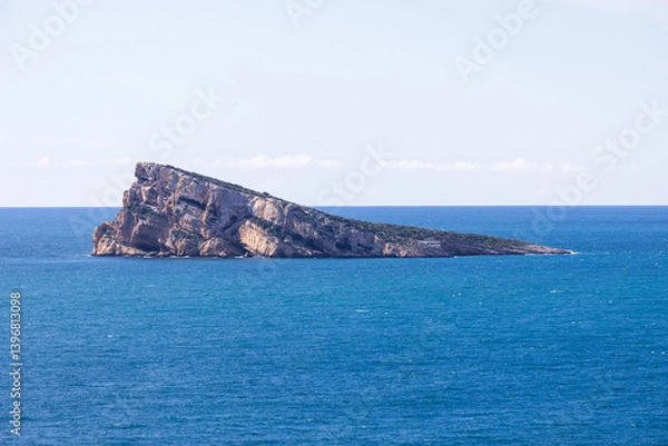 Fototapeta Photo located in the town of Benidorm in Spain showing the rock in the middle of the ocean known as Isla de Benidorm or Mirador de l'Illa de Benidorm with a blue sky on a sunny day
