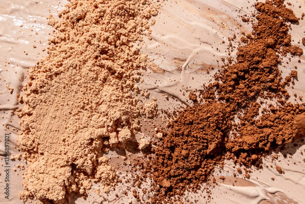 Fototapeta Evenly spread layers of foundation in various shades covered with scattered piles of powder products in matching tones