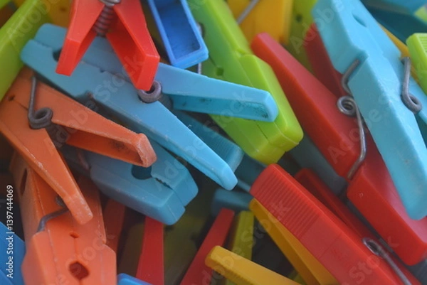 Fototapeta Colorful clothespins in a messy pile on a bright background during daylight