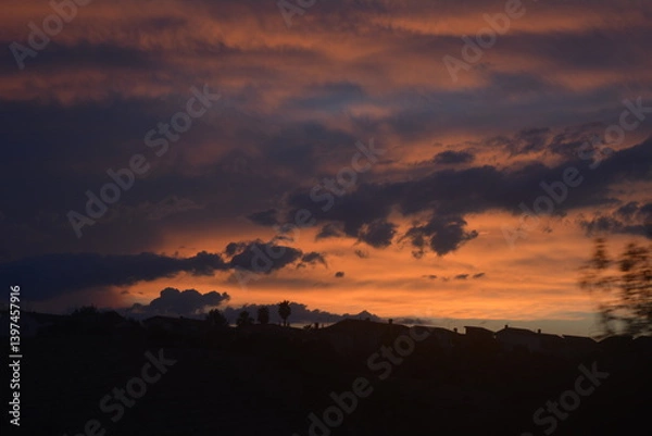 Fototapeta Beautiful sunset with vibrant colors and silhouette of buildings against the horizon in a tranquil evening sky