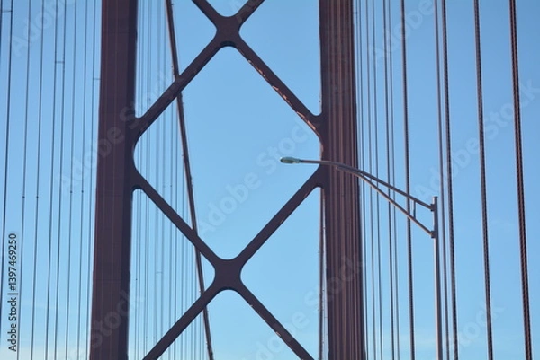 Fototapeta View of bridge cables against a clear blue sky with a streetlight in the foreground at midday