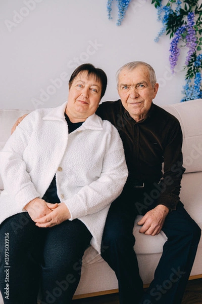 Obraz Elderly Couple Sitting Together on a Couch at Home