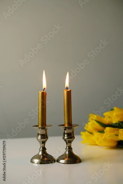 Obraz Stylish Shabbat setup with glowing candles and fresh yellow tulips. A warm and elegant image symbolizing Jewish tradition, peace, and family togetherness. Perfect for holiday, spirituality