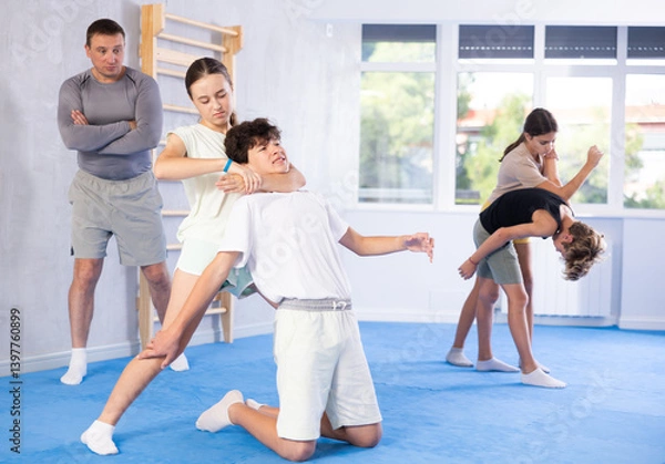Fototapeta Boy and girl training self-defense techniques in group in studio