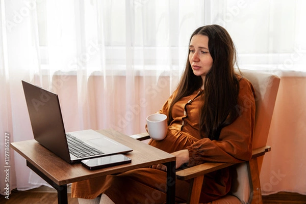 Fototapeta Tired pregnant woman is working with laptop at home. Remote work for pregnant women concept.