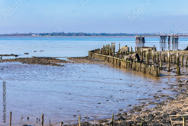 Fototapeta A pier over the river thames viewed from the Cliffe RSPB nature reserve near Gravesend in Kent, England