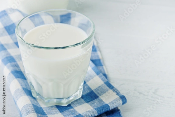 Fototapeta Milk in jug and glass on wooden table and blue background. Concept of farm dairy products, milk day. Kitchen or supermarket mock up for design. Copy space.
