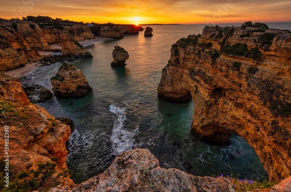 Obraz Dramatic cliffs and rock formations at sunset in Algarve, Portugal, with a vibrant sky and tranquil waters.