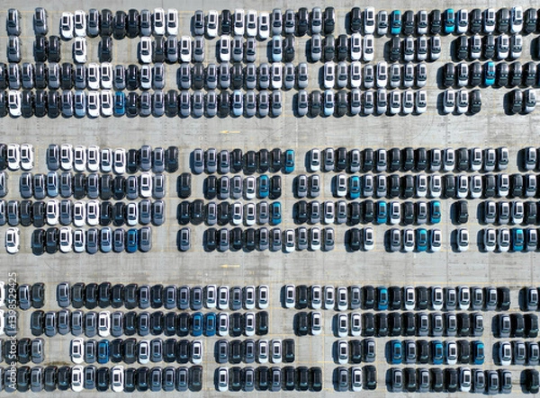 Obraz Aerial view of new cars stock at factory parking lot. Above view cars parked in a row. Automotive industry. Logistics business. Import or export new cars at warehouse. Big parking lot at port terminal
