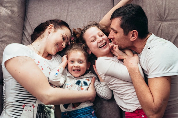 Fototapeta Happy family lying on the couch and laughing