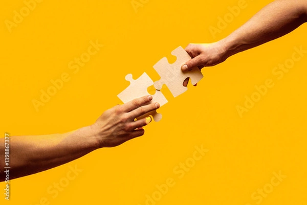 Fototapeta Teamwork concept. Close Up hand of connecting jigsaw puzzle. Two hands trying to connect couple puzzle piece on yellow background