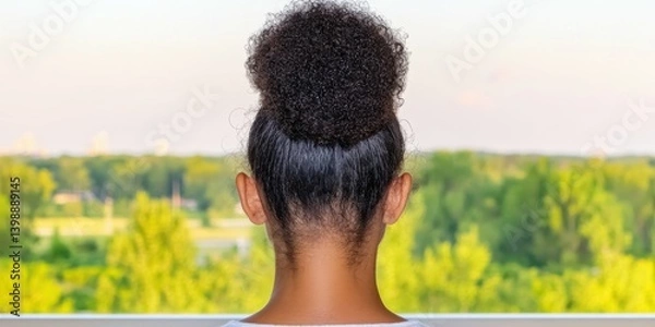 Obraz A woman with a ponytail is looking out the window. The view outside is a green forest with trees and a lake