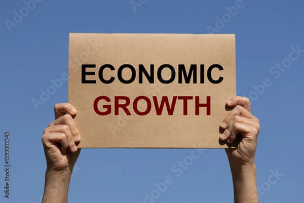 Fototapeta Economic growth text on brown paper holding by 2 hands of a man