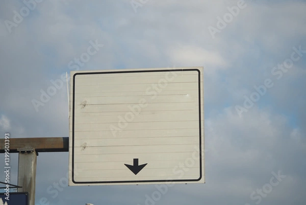 Obraz Blank traffic sign points downward amidst a cloudy sky