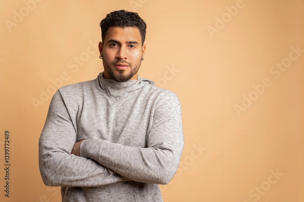 Fototapeta Colombian man posing with crossed arms in studio on beige background