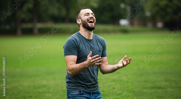 Fototapeta Joyful man laughing while standing in a green park  