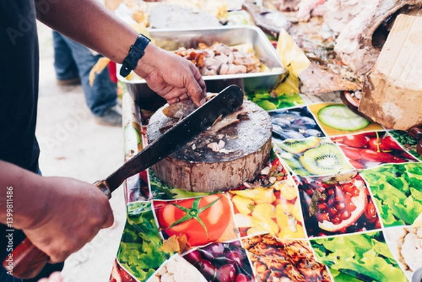Fototapeta Man's hand slicing on wooden chopping board of the popular, delicious and crispy roasted pig known as "lechon baboy" (in the Philippines, Spain, Cuba, etc.). Selective focus. Copy space.