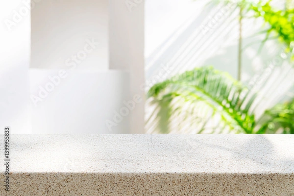 Fototapeta Tropical stone table top as mock up for product display montage on blurred white architecture background in sun light and shadows with green tropical plant leaves