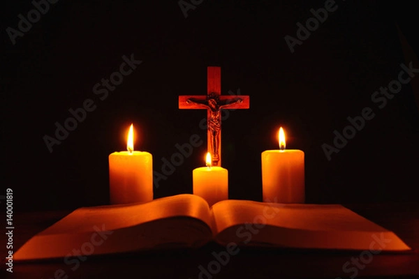 Fototapeta Crucifix and three burning candles with open bible on table in the darkness. Pray to Jesus Christ. Hope on good life. 4