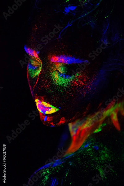 Fototapeta Beautiful extraterrestrial model woman in neon light. It is portrait of beautiful model with fluorescent make-up, Art design of female posing in UV with colorful make up. Isolated on black background