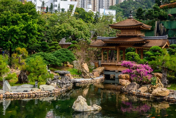 Fototapeta A tranquil pond with koi fish swimming in its clear waters at Nan Lian Garden, Hong Kong. The pond is surrounded by lush greenery and a traditional Chinese style pavilion.