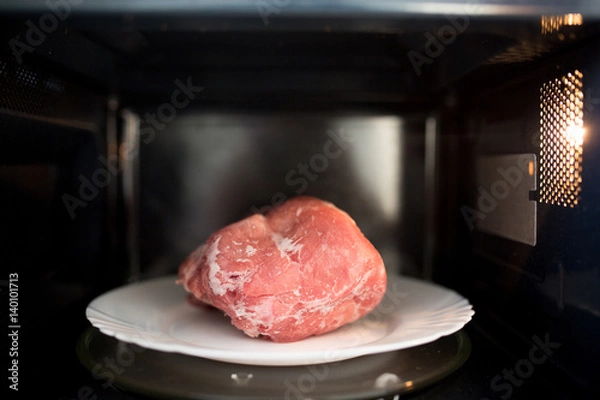 Fototapeta Frozen pork defrosted in the microwave