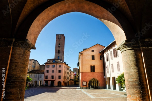 Fototapeta Piazza Risorgimento, main square of Alba (Piedmont, Italy) seen through the colonnade of Saint Lawrence Cathedral