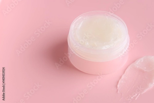 Fototapeta Moisturizing lip balm and jar on pink background, closeup. Space for text