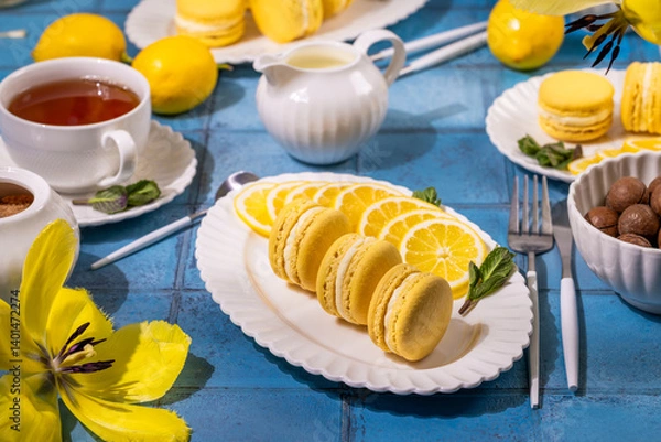 Fototapeta Lemon macarons with tea and nuts on blue table setting