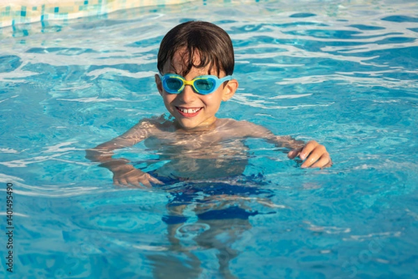 Obraz Child wearing swimming goggles swim in a pool on a sunny day.