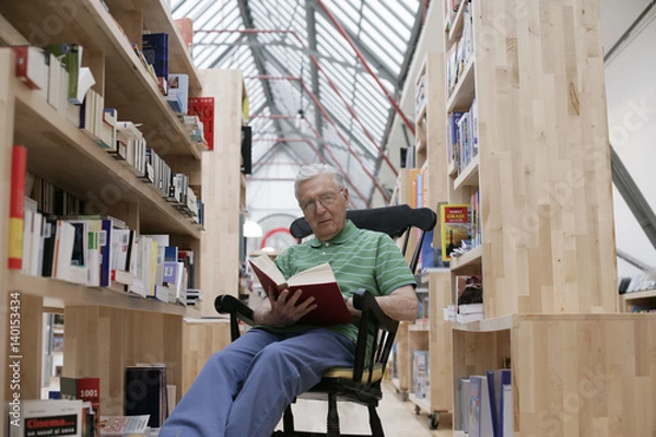 Obraz Senior man in a rocking chair reading a book, fully_released