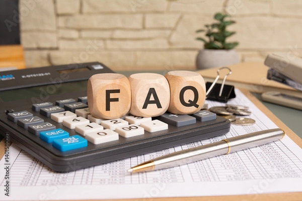 Fototapeta Wooden blocks with "FAQ" on a calculator surrounded by coins, papers, and a pen