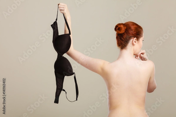 Obraz Naked woman holds black bra in hand