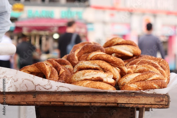 Obraz Freshly baked simit displayed on a wooden cart in a bustling market