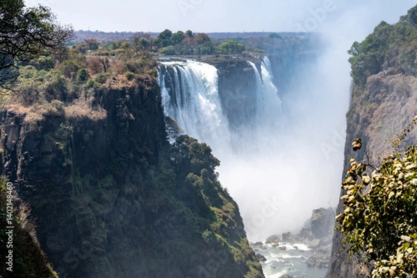 Fototapeta Victoria Falls in Zimbabwe viewed from the front with water cascading down on a sunny blue sky day 