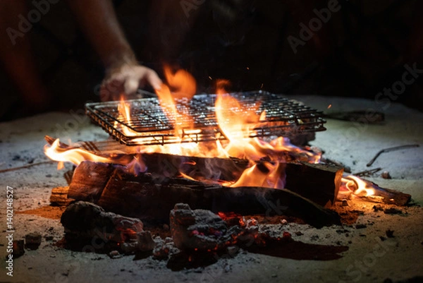 Fototapeta Meat in a grill grate being grilled on  an open fire in Botswana Africa in the night 