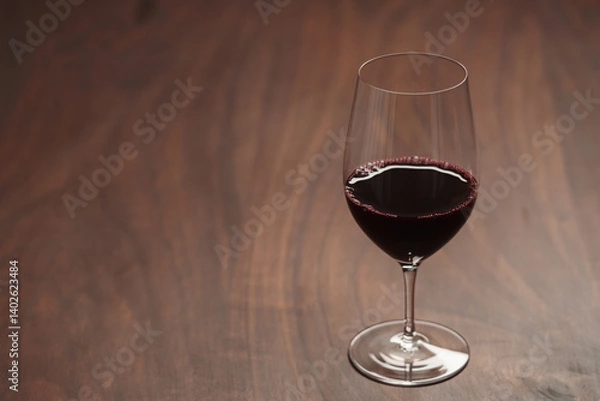 Obraz Red wine in wineglass on black walnut table with copy space