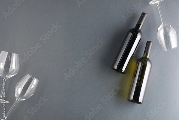 Fototapeta Bottles of wine and glasses on grey background, flat lay. Space for text
