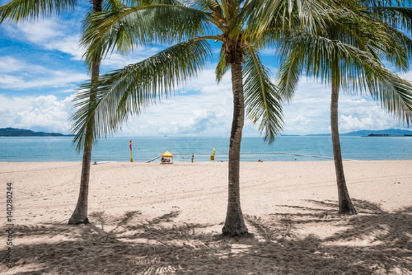 Fototapeta People enjoying a swim on tropical beach, The Strand, Townsville, Australia while a lifeguard keeps watch