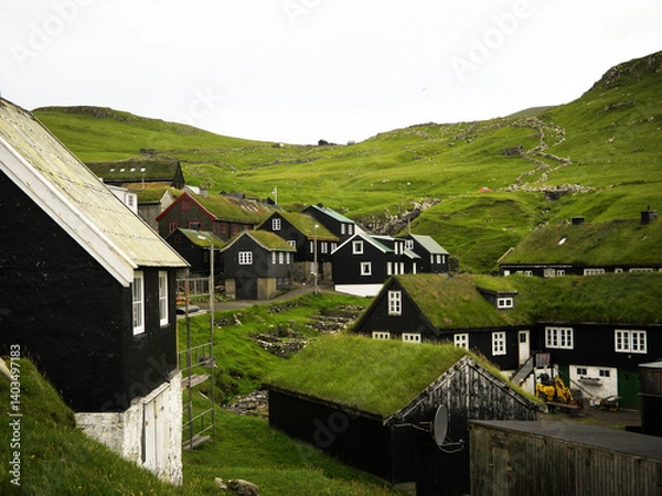 Obraz Typical faroese wooden houses with grassy roofs  hides under mountain. This village at the edge of Atlantic ocean called Mykines evokes remotennes, solitude and harsh life on the Faroe Island