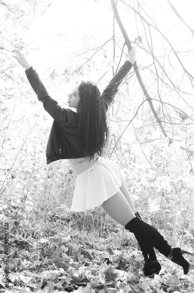Fototapeta Close-up portrait of a fantastic young model girl posing in the park on a sunny day. Black and white photo.