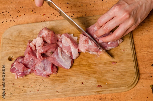 Fototapeta Female hands with a knife in their hand cut fresh meat on a table