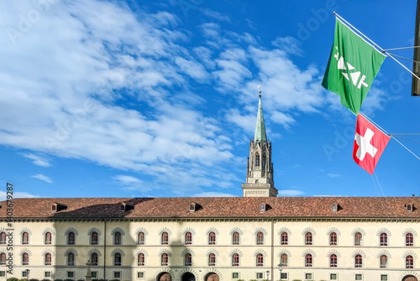 Fototapeta Sunny day view of St. Gallen Abbey's historic facade and cathedral spire, a UNESCO World Heritage site in Switzerland, with national and cantonal flags