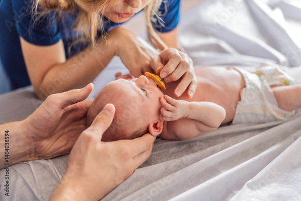 Fototapeta A newborn baby receives gentle osteopathic care, lying calmly while the specialist carefully examines and adjusts the infant. A moment of professional pediatric care, early development, and holistic