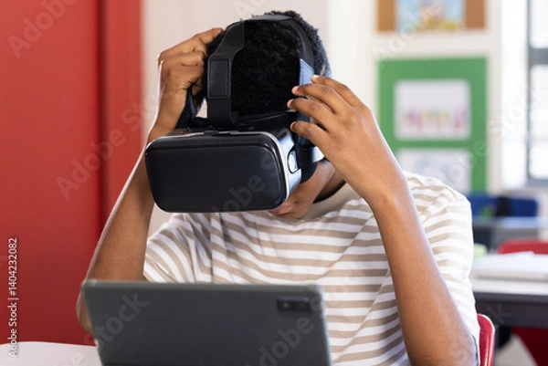 Obraz Using VR headset, student exploring virtual reality with tablet in school classroom